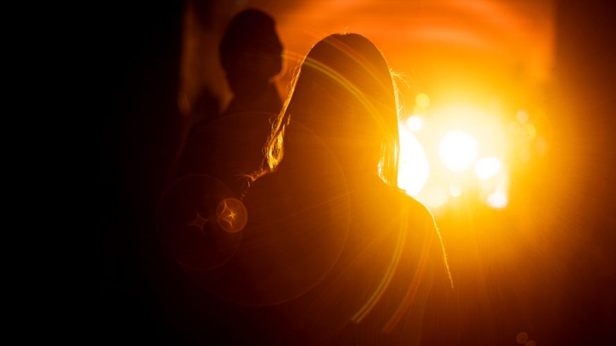 Silhouettes of people in front of a sun glare